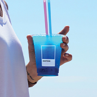 woman holds a blue colored drink at the pantone cafe