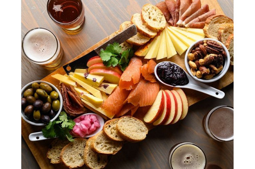A charcuterie board of food including apples, cheeses, veggies, crackers, nuts and more. This colorful, vibrant, well-light view is the secret to a great tourism photo.