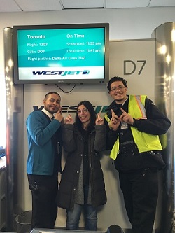Chris Miranda stands between two WestJet employees at the gate in an example of unexpected and fabulous tourism guest service experiences.
