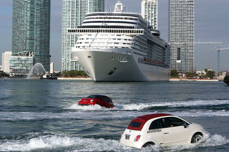 a red and a white fiat in the water escorting msc cruise ship