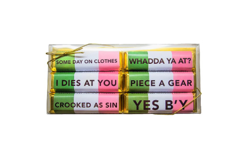 A collection of six chocolate bars, each with a green, white, and pink wrapper featuring black type with a saying on it. This is an excellent example by the Newfoundland Chocolate Company to inspire word-of-mouth in tourism marketing, as each phrase is a distinctive saying by Newfoundlanders, such as "I dies at you."