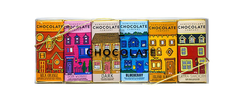 A collection of six chocolate bars in a clear package, each with a picture of a different color house on it: orange, pink, yellow, blue, red, and tan.