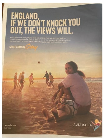 A newspaper ad that shows a young woman with a soccer ball in the foreground and a group of kids playing in the background on a beach, with the headline "England, if we don't knock you out, the views will."